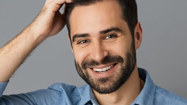 Smiling man with thick hair showcasing results of a successful hair transplant, promoting affordable FUE & DHI procedures in Dubai and the UAE.